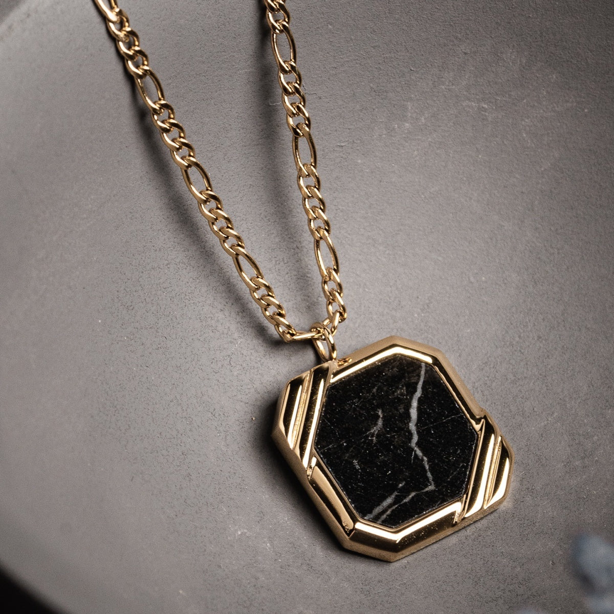 Collana "Scalar" presenta un audace pendente in marmo esagonale con accenti in oro, offrendo un look moderno e sofisticato.