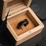 "Countless Ring", a stylish ring made of maple and dark grey material, elegantly displayed in a wooden box.