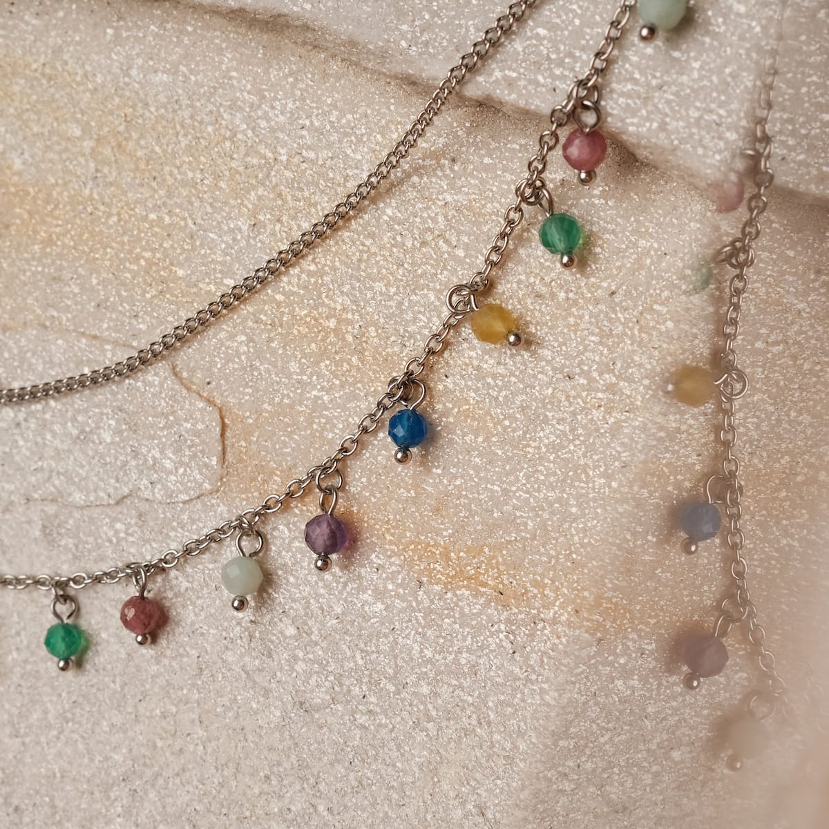 "Free Play Necklace", a necklace with rainbow beads on a silver chain, exudes a playful and vibrant style.