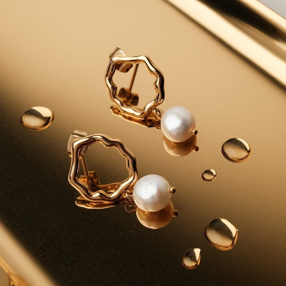 "Oceanfoam Earrings" earrings feature a pearl and gold design with an ocean-inspired style.