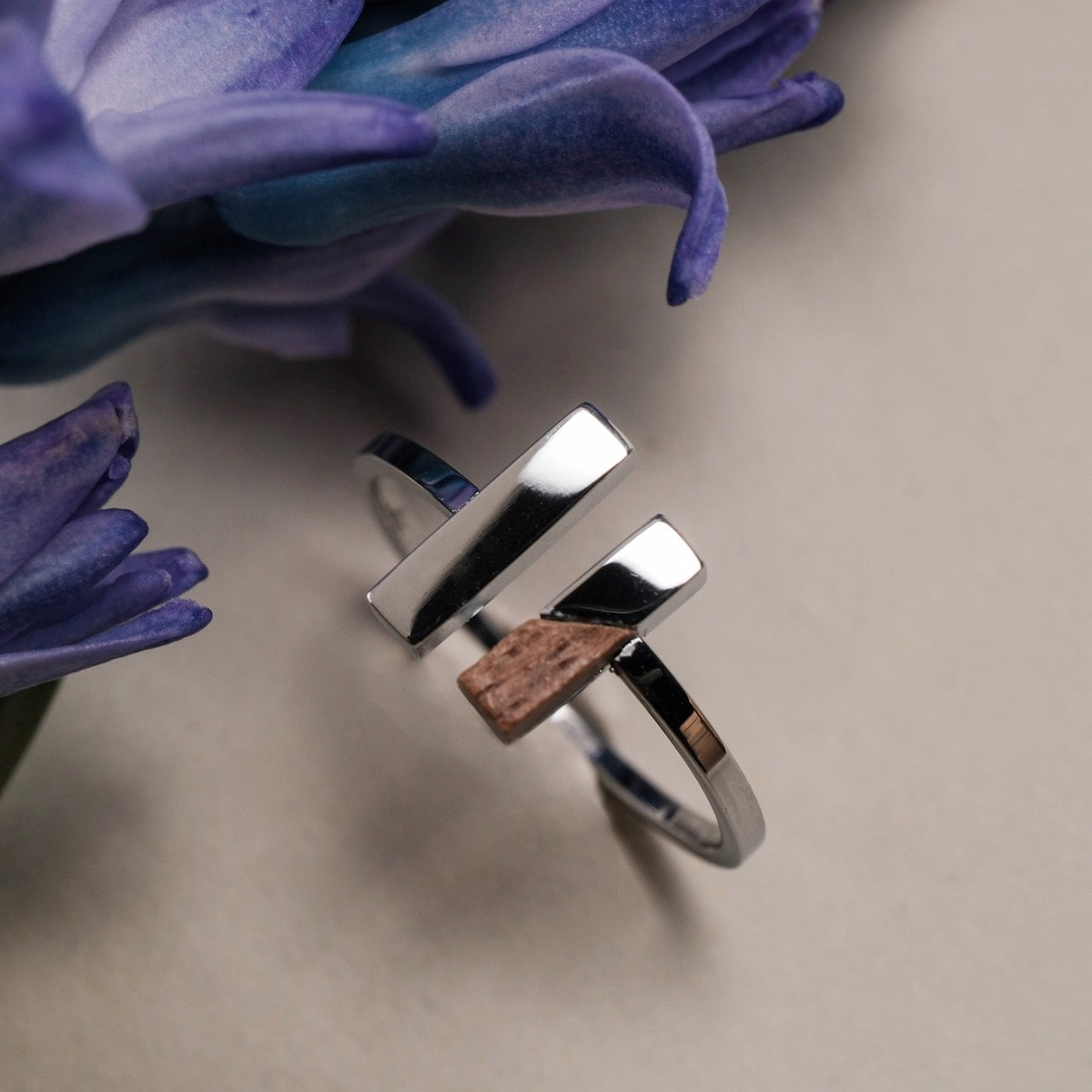 "Campania Ring": Modern ring featuring walnut and silver accents alongside delicate blue petals.