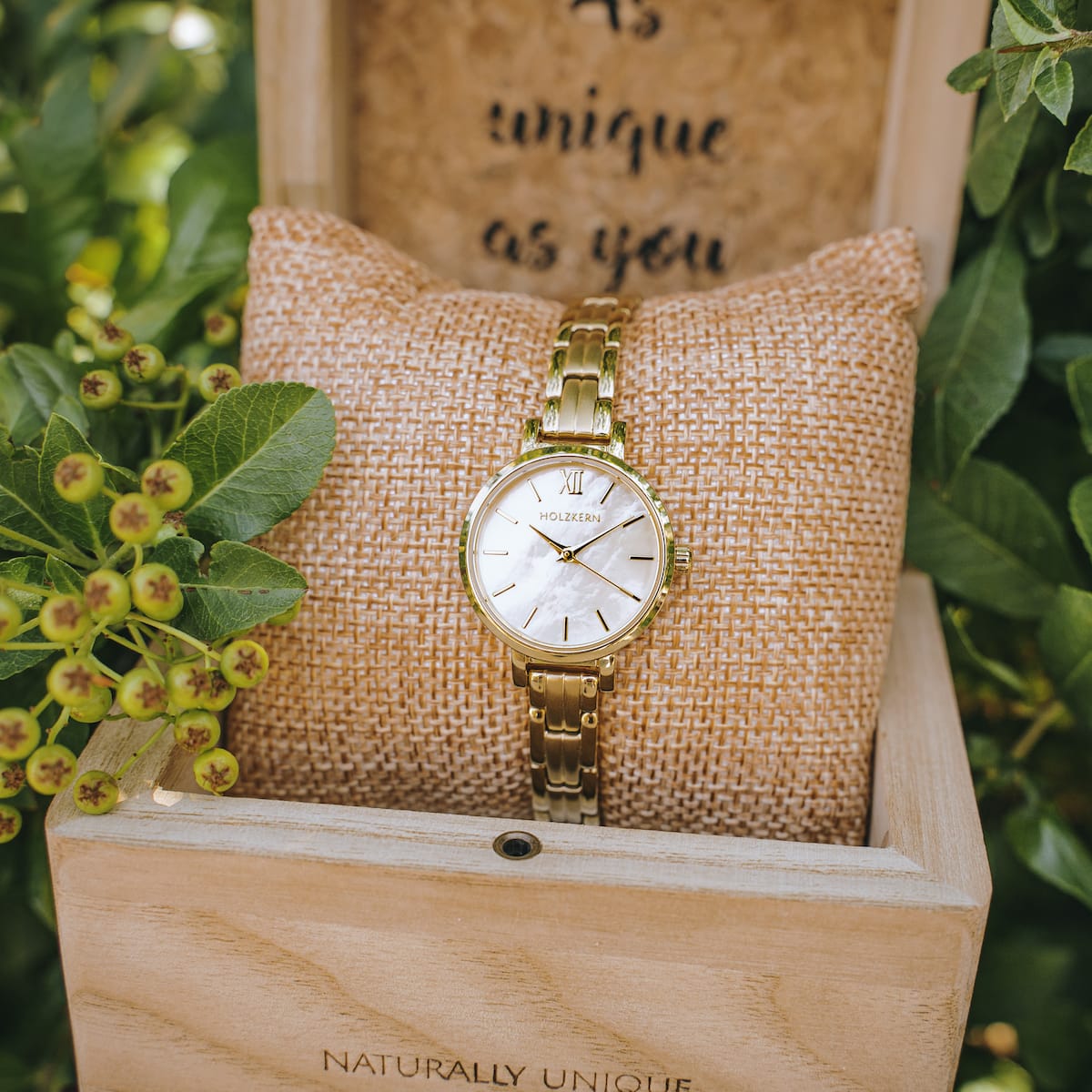 "Hanwi" watch with nacre dial and gold-tone band, presented stylishly on a cushion in a wooden box.