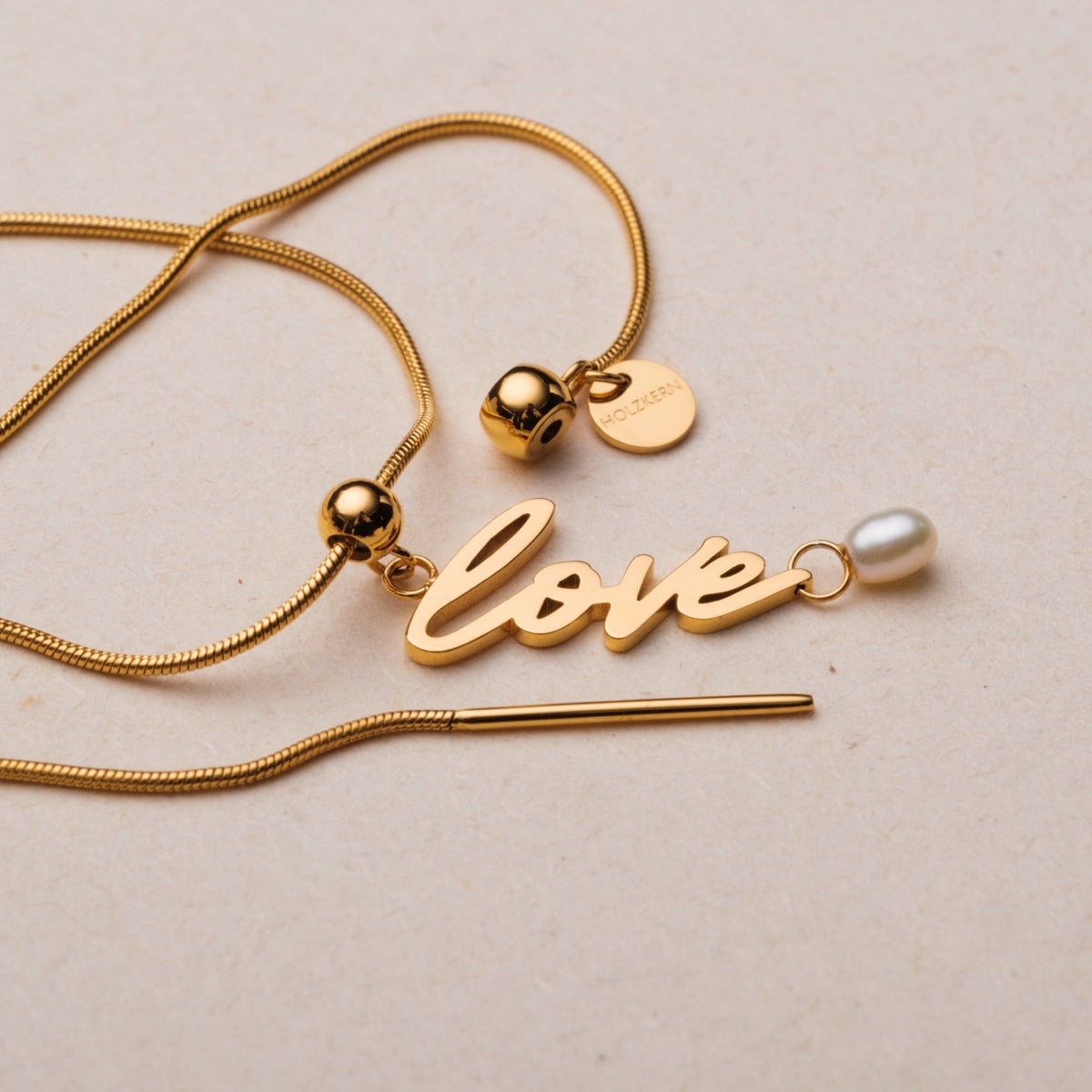 Collana "Love-Charm" con elegante finitura oro e perla accento in un design elegante.