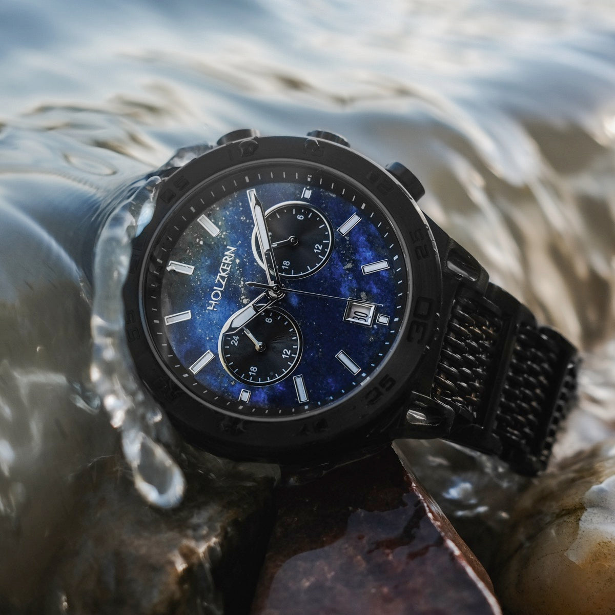 Orologio "Aoraki" con quadrante lapis lazuli e accenti neri, con un design elegante cronografo in un ambiente dinamico dell'acqua.