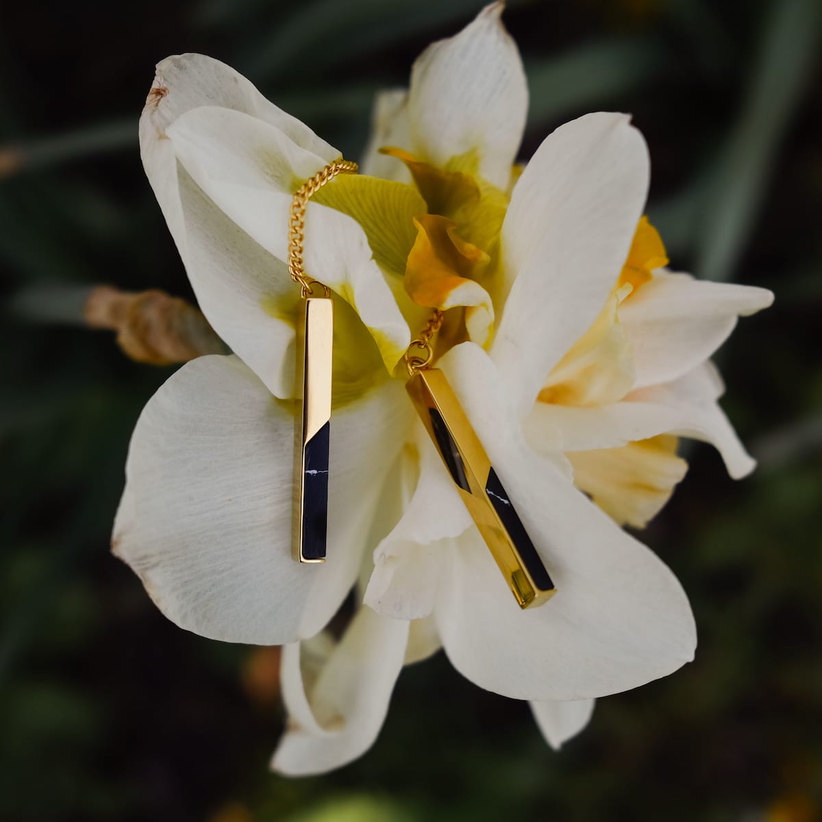 "Campania Earrings earrings, featuring a sleek marble and gold design, elegantly displayed on a white flower."