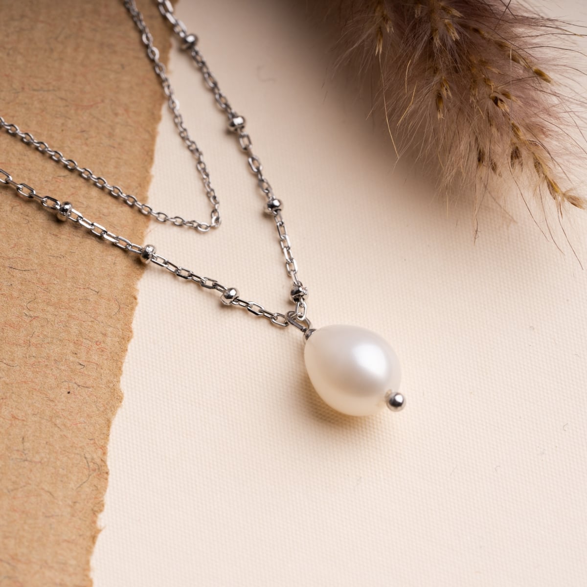 "Panoramic Necklace": A silver necklace featuring a white pearl, showcasing elegant and sophisticated style.