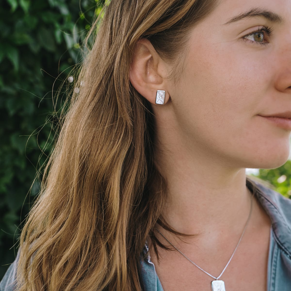 "Aquarell Earrings" earrings with a modern white nacre and silver design, elegantly worn by a woman.