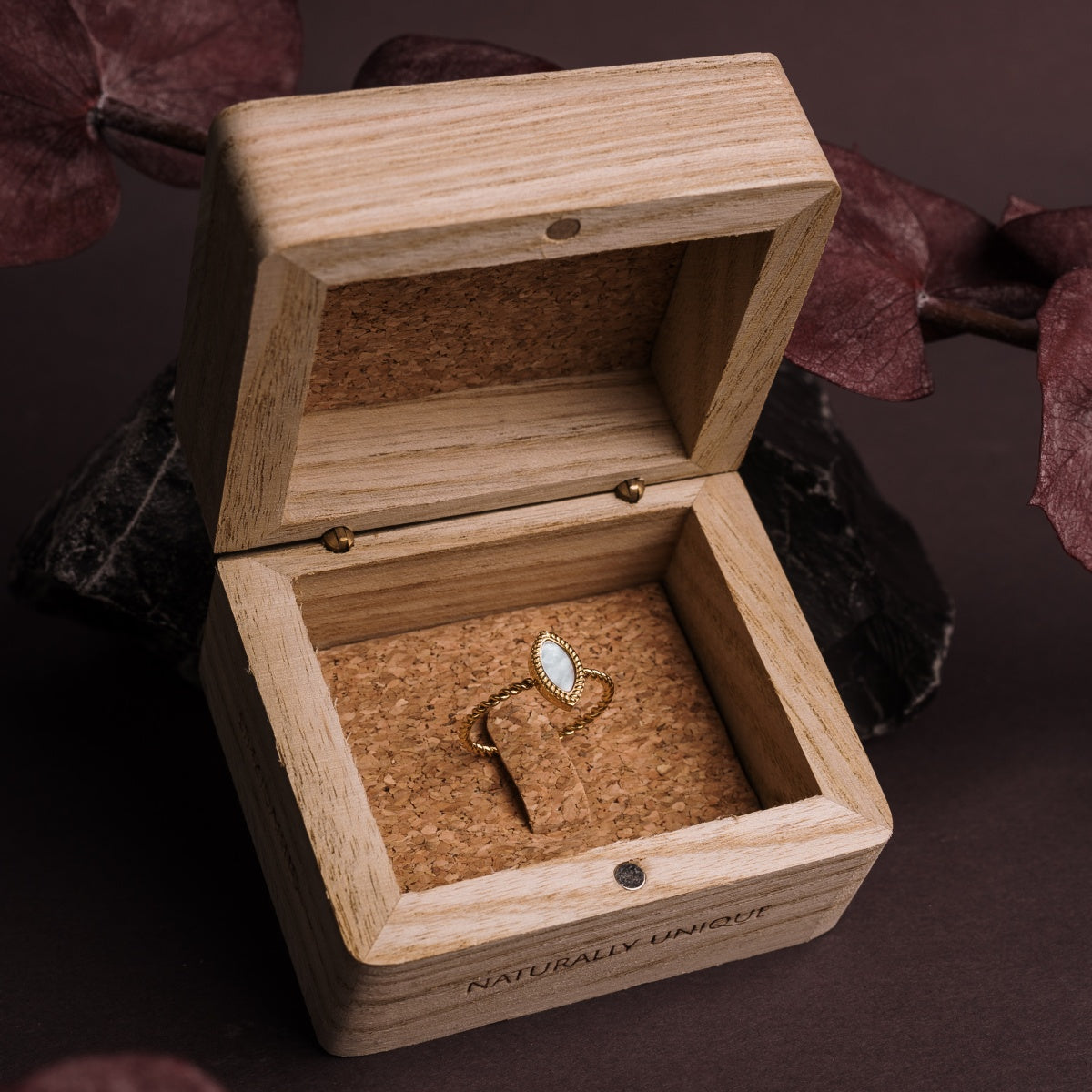 "Anello Visuale", anello in oro con nacre bianco, esposto in una scatola in legno rustico per un elegante appeal visivo.