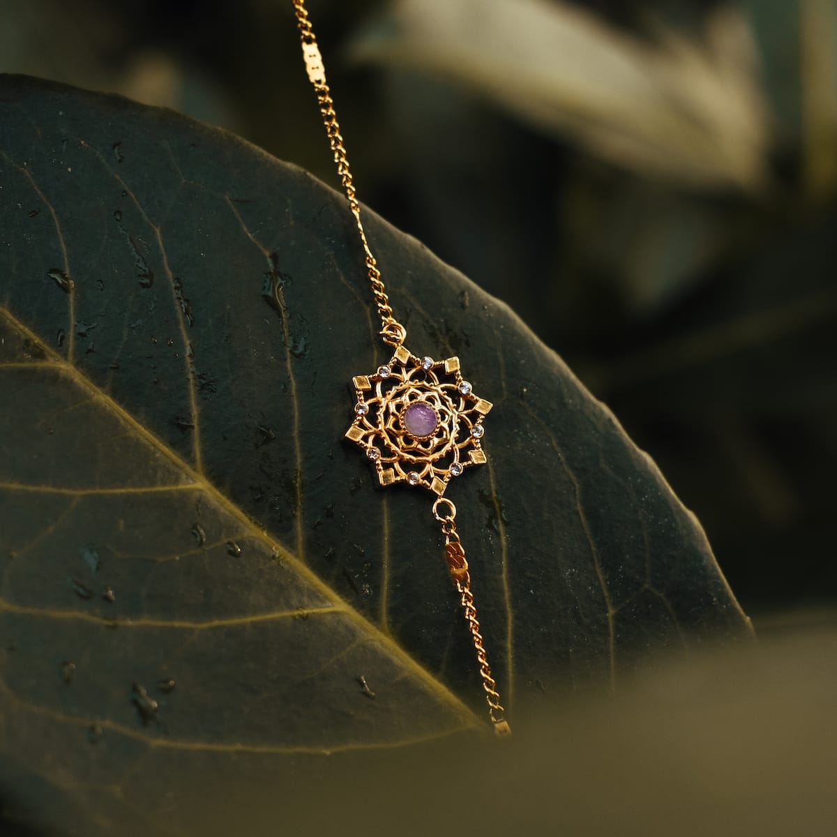 Bracciale "Aphonia" con ametista e oro, che mostra un design intricato su un fondo naturale.