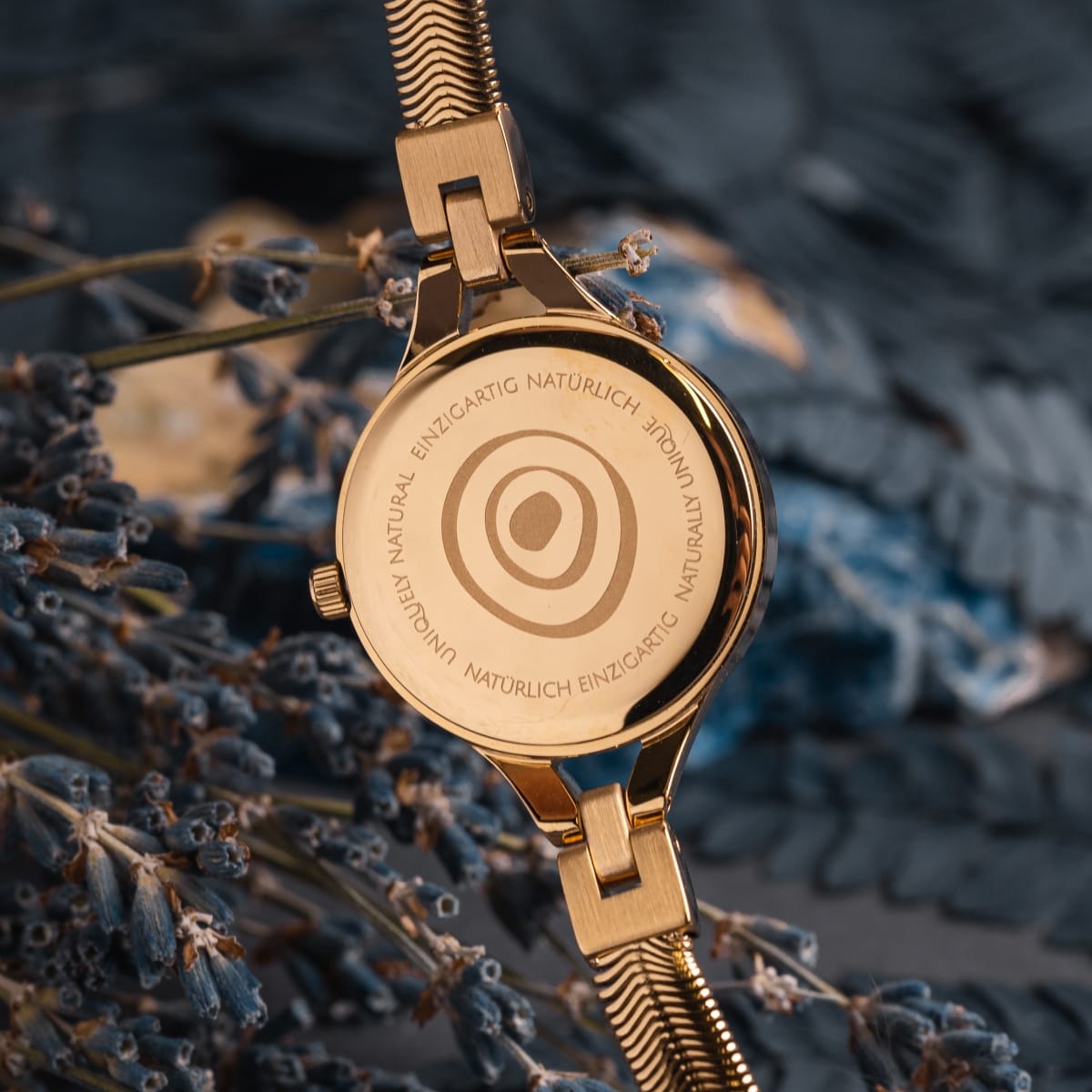 "Shesha", un orologio d'oro con un design elegante e sofisticato, evidenziato da nacre dettagliando su uno sfondo naturale.