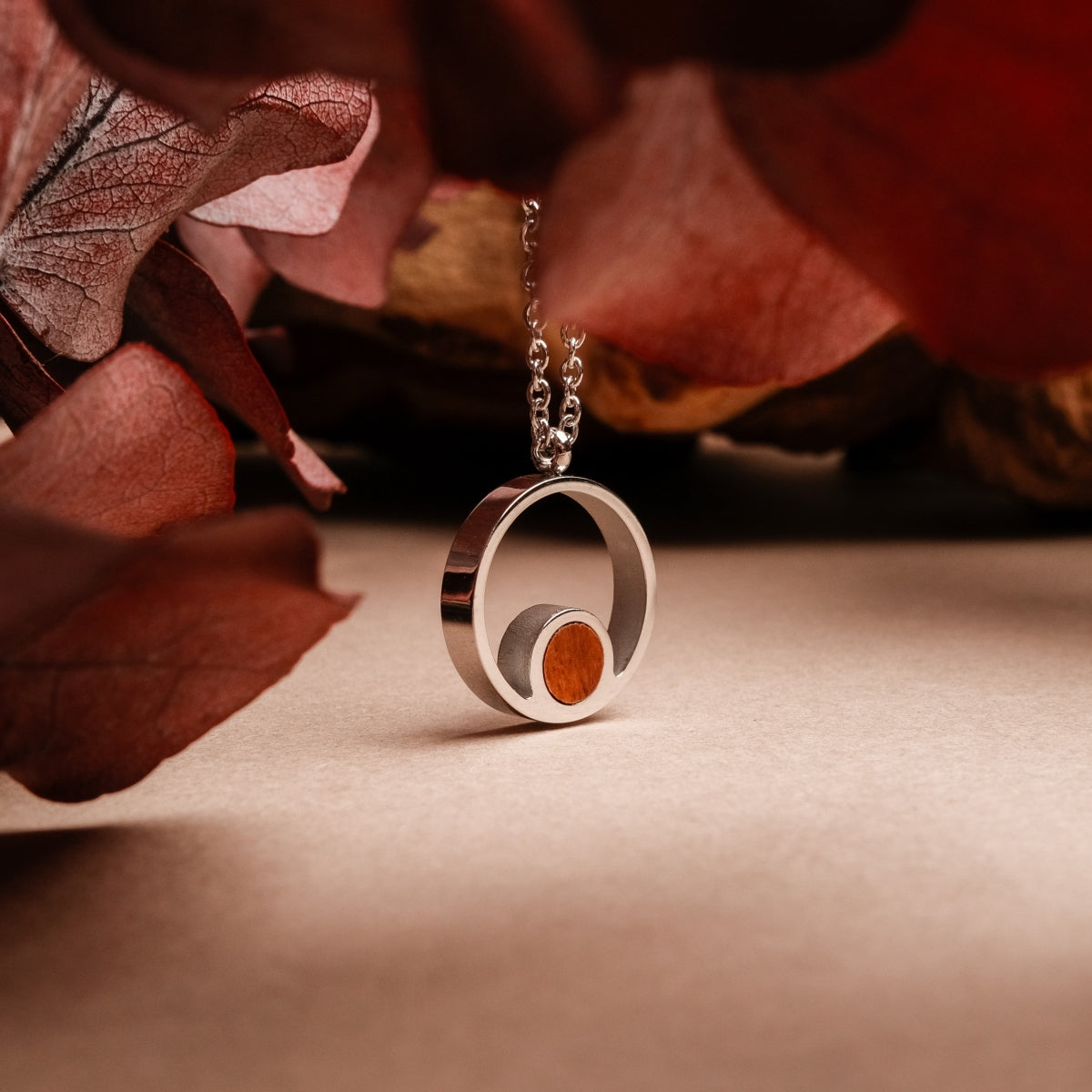 "Collana del pigmento": Elegante collana con un ciondolo in legno di koa e argento su uno sfondo caldo e terroso.
