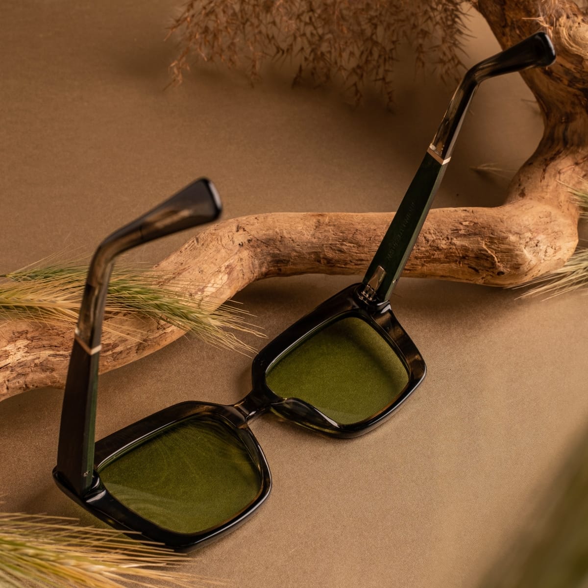 "The Exquisite sunglasses, featuring a Leadwood/Khaki Dust design, laid-back and stylish on a rustic background."