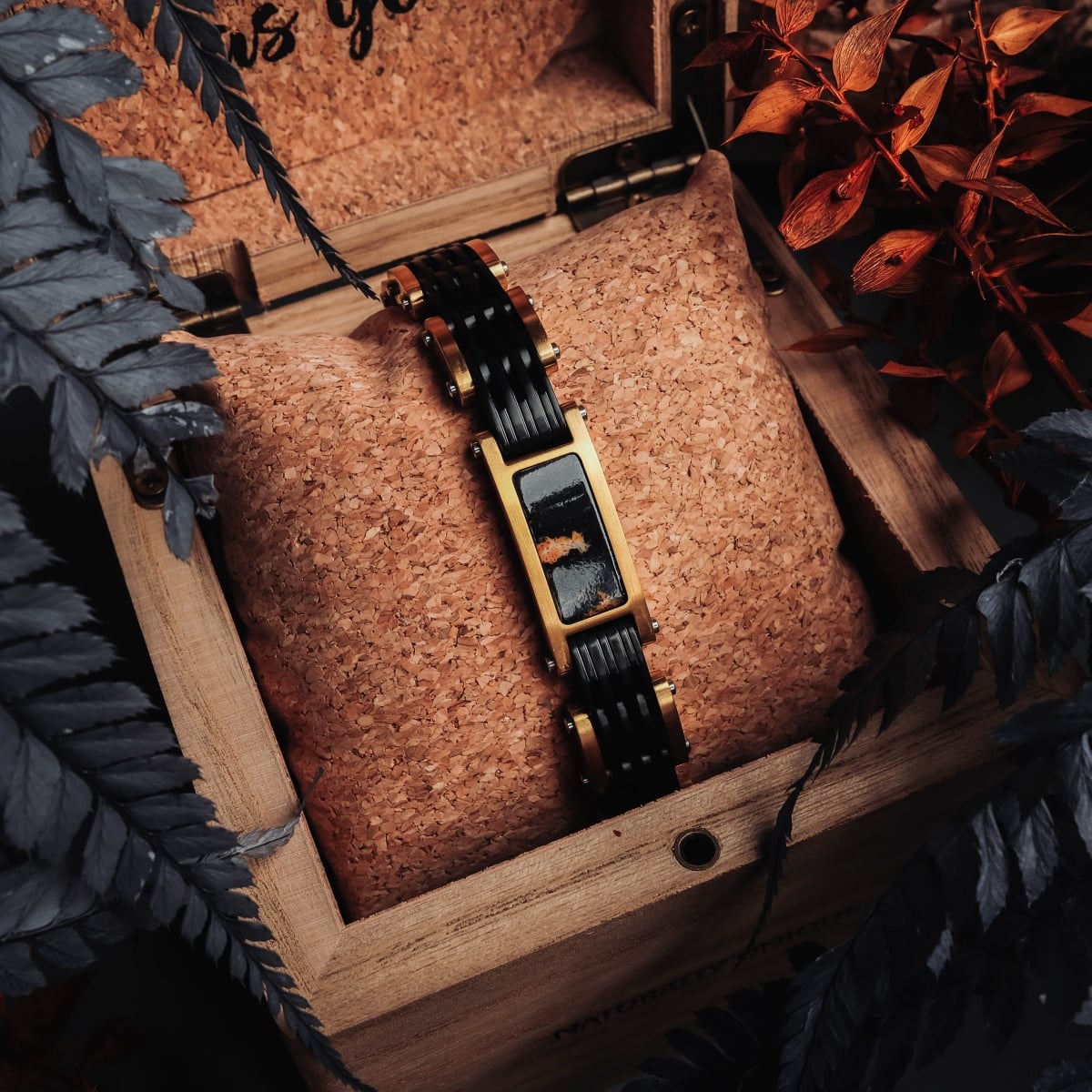 "Adagio" bracelet with a marble and gold design in an elegant wooden box, surrounded by foliage.
