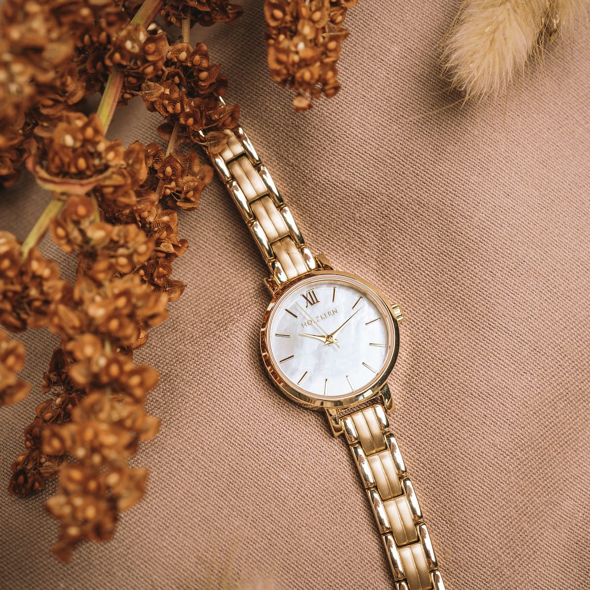 "Hanwi" watch featuring a nacre dial and gold bracelet, styled with an elegant and natural aesthetic.