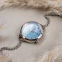 "Brighter", un elegante orologio da polso con un quadrante nacre e accenti d'argento, elegantemente presentato con un braccialetto a catena.