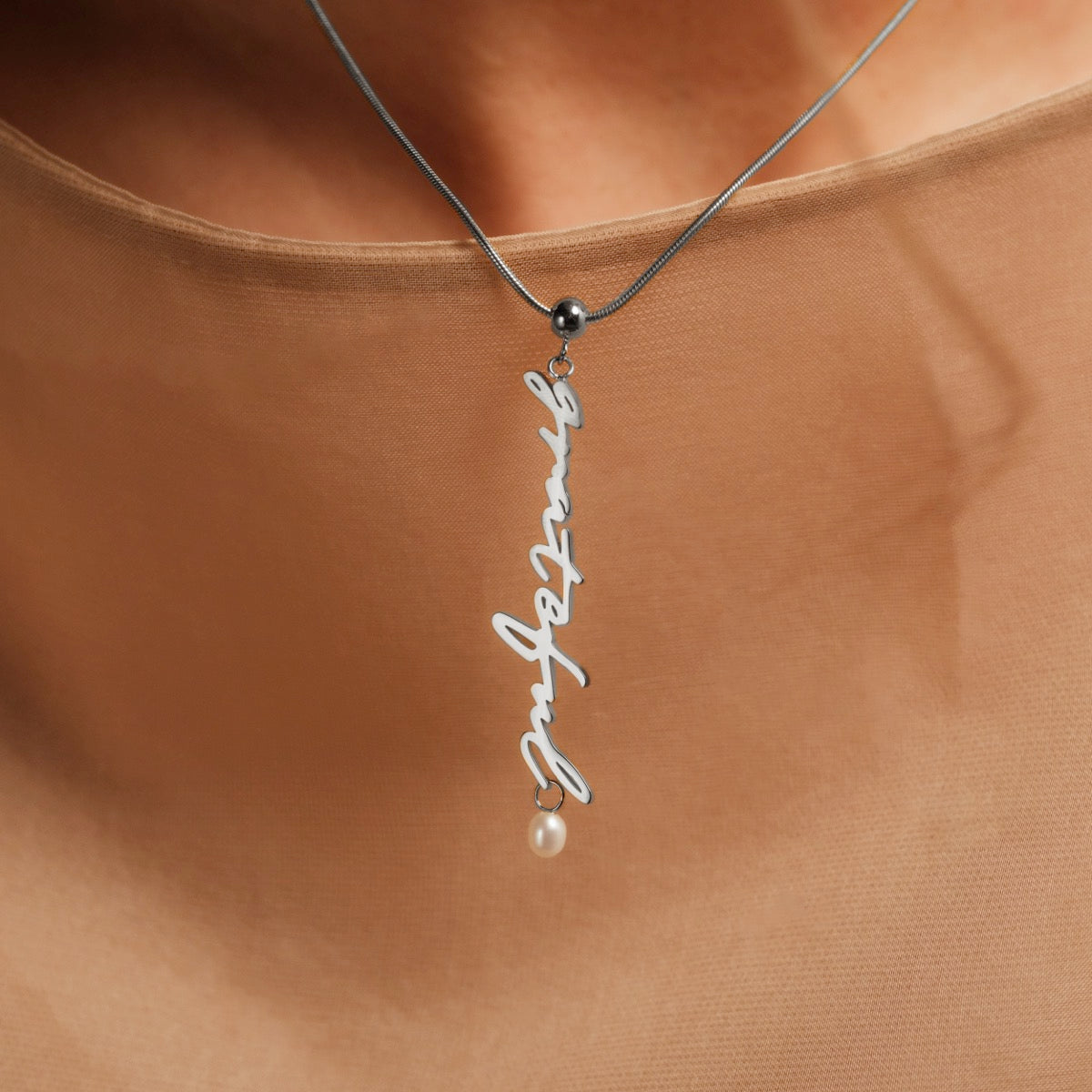 "Grateful-Charm", elegante collana con un fascino argento e perla accento, che mostra un design elegante e minimalista.