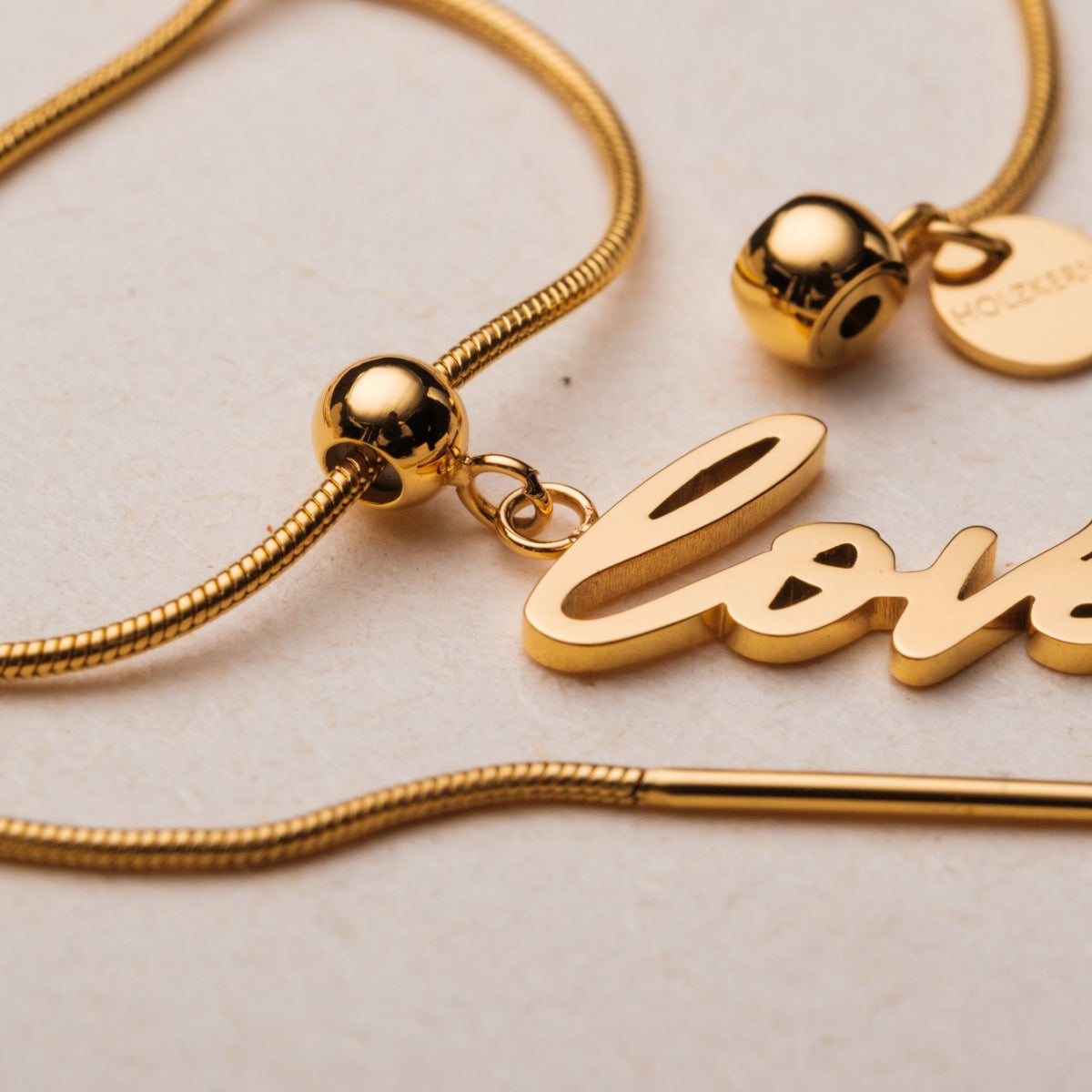 Bracciale "Love-Charm": elegante script in oro con delicati accenti perla.