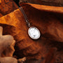 "Mirror Necklace": Elegant necklace with turquoise stone and rose gold accents, styled on autumn leaves.
