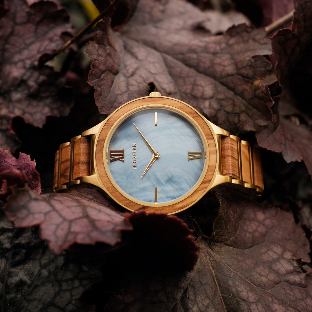 Orologio "Capri" con finitura in legno naturale e design elegante tra ricchi fogliami.