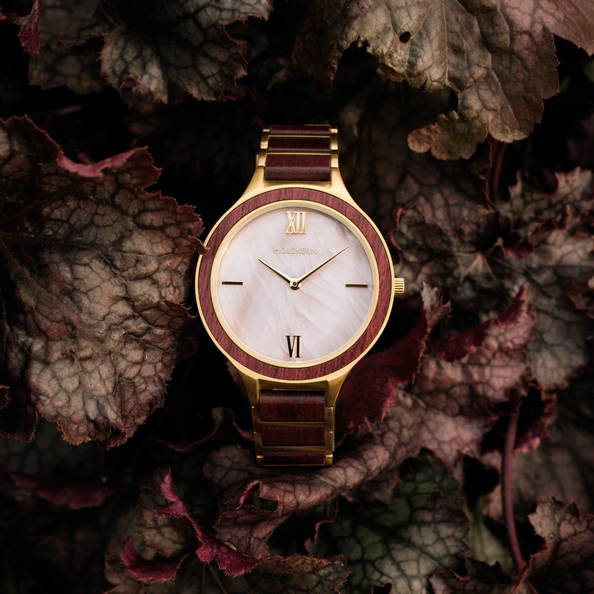 "Mauritius" watch, featuring an elegant amaranth and nacre style, set against a backdrop of textured leaves.