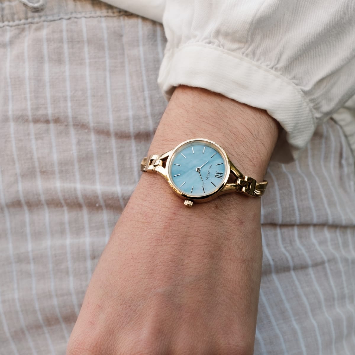 "Shesha" orologio, con un quadrante e un design in oro, elegantemente in stile su un polso.