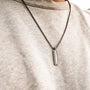 Collana "Planarity Collana" in marmo e grigio scuro, con un elegante e minimalista ciondolo dall'estetica moderna.