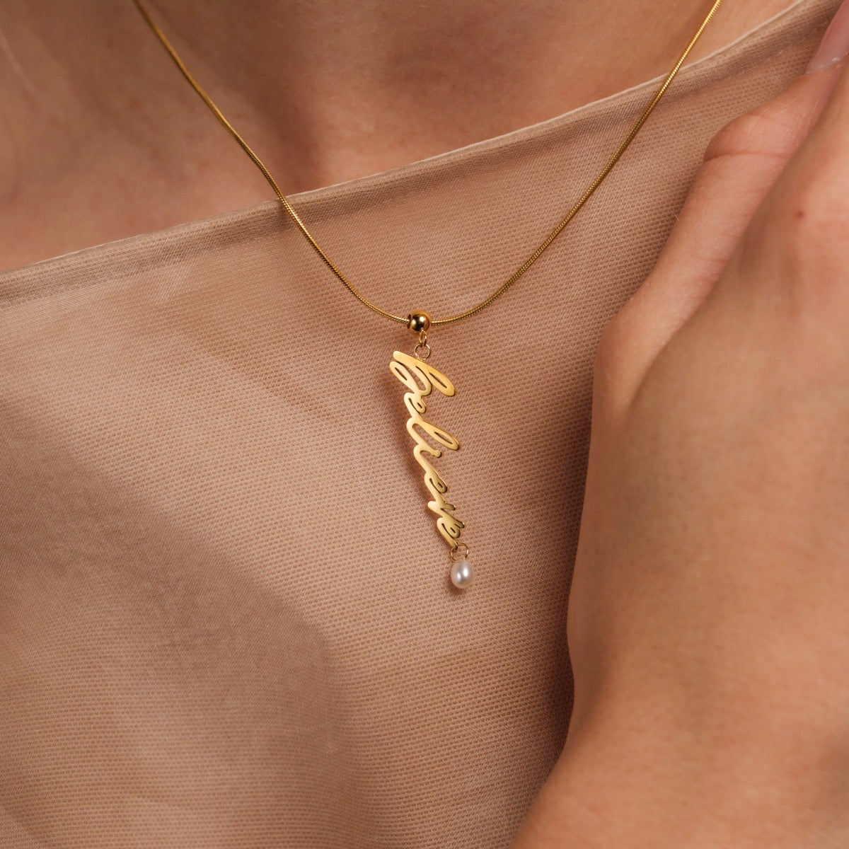 Collana "Believe-Charm", un fascino d'oro con un accento di perla e un design elegante script.
