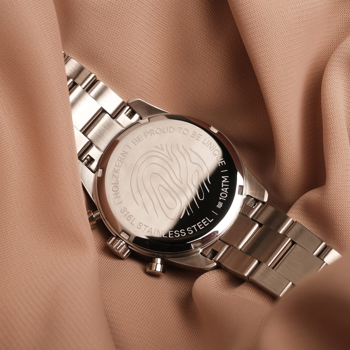 Orologio "The Balanced" con accenti in argento e nacre, caratterizzato da un design elegante e moderno su uno sfondo in acciaio inox.