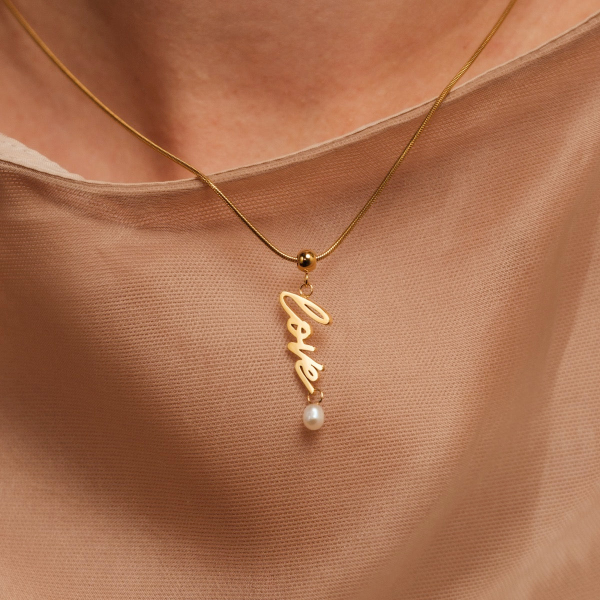 Collana "Love-Charm", con scritte in oro e perla, progettata con uno stile elegante e delicato.