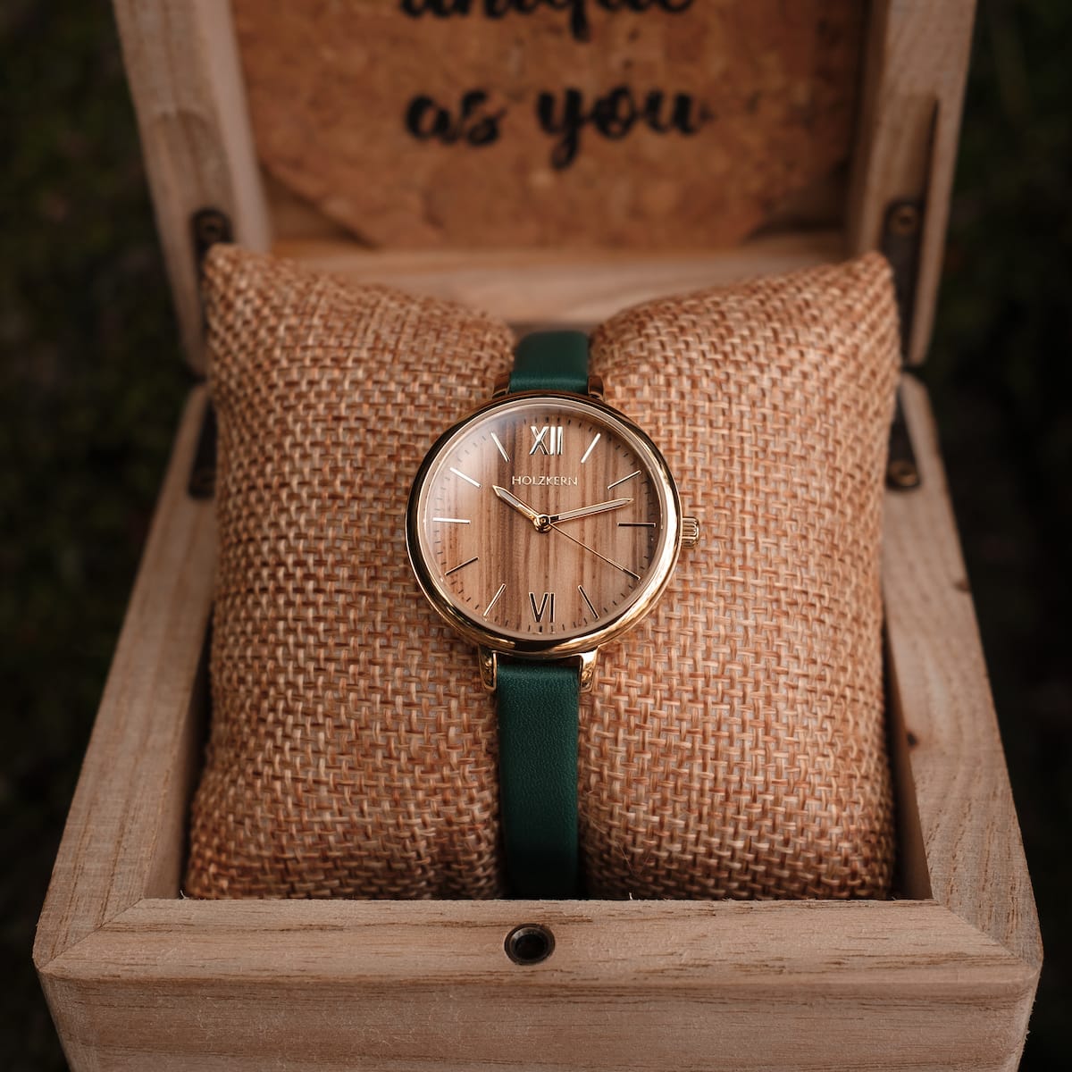 "Wangari" watch with zebrawood face, gold accents, and green strap, in an elegant display box.