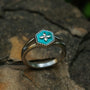 "Spectral Ring", un anello in argento e nacre che mostra un design floreale turchese su una band strutturata.