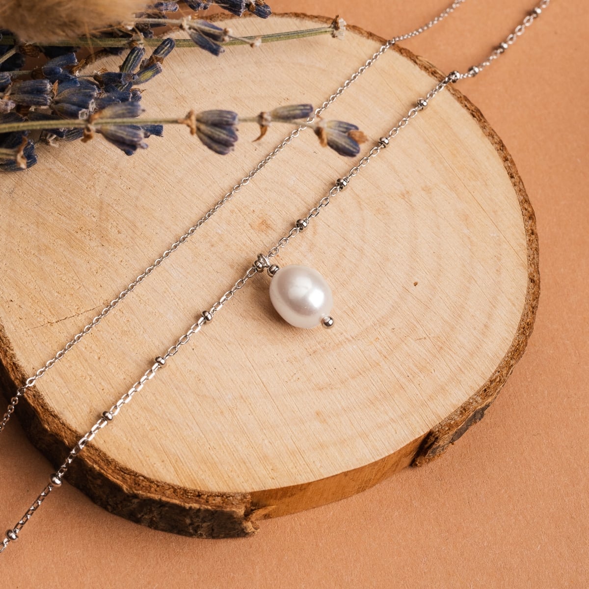 "Panoramic Necklace" necklace featuring a white pearl and silver chain in an elegant style on a rustic wood background.