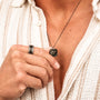 "Collana in cristallo", una collana elegante grigio scuro con finitura Nero Portoro, presentata contro una camicia con texture.