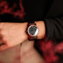 "Passion", un elegante orologio da polso realizzato da Padauk e Maple, presenta un design sofisticato su un polso.