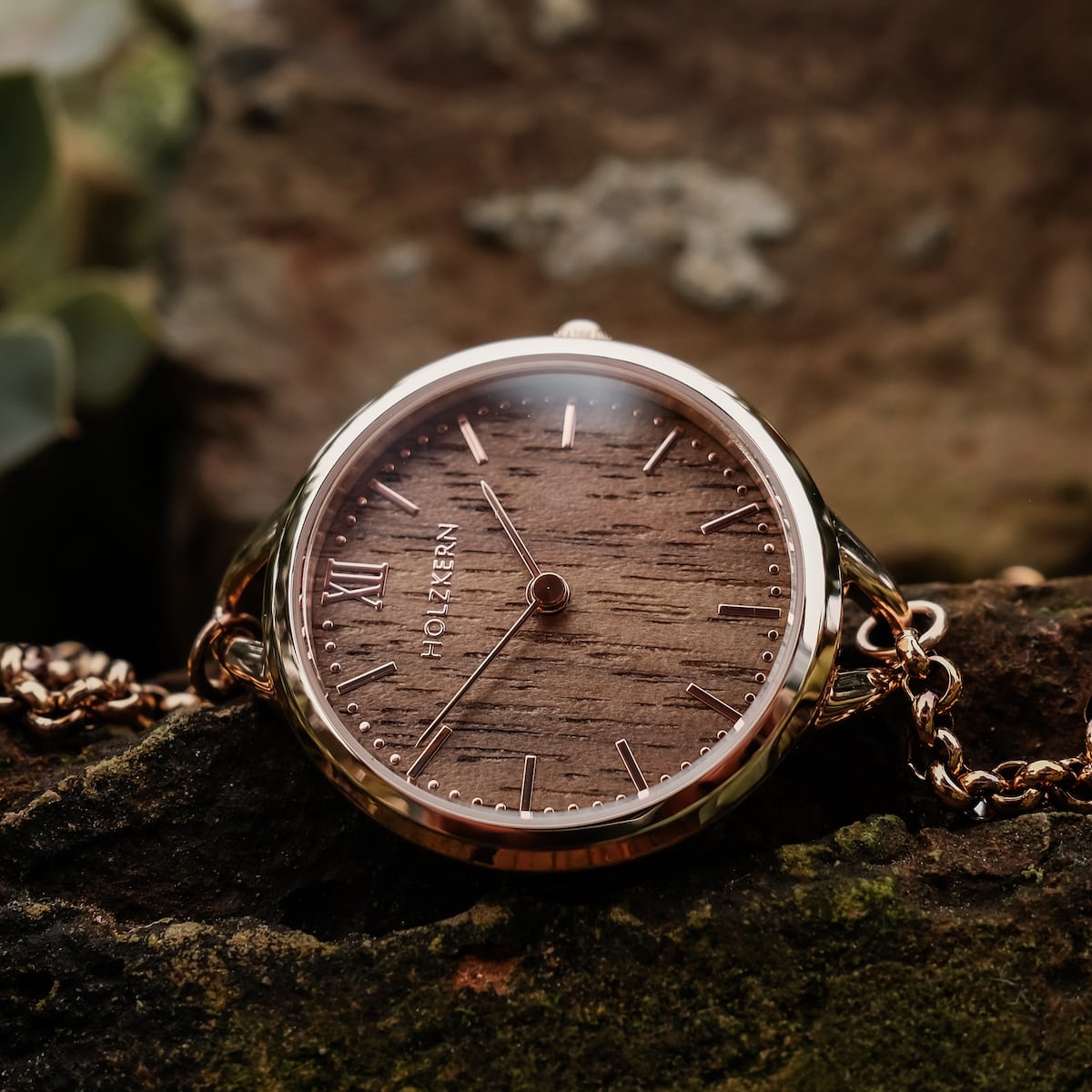 Orologio "Blissed" con legno di noce e accenti in oro rosa su uno sfondo rustico.