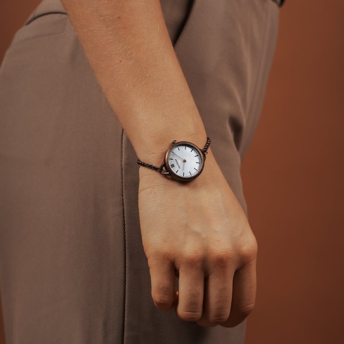 "Touching" watch featuring a nacre face and antique copper accents, elegantly styled on the wrist.