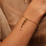 Bracciale "Believe-Charm" con elegante lettering in oro e una perla delicata, in stile al polso.