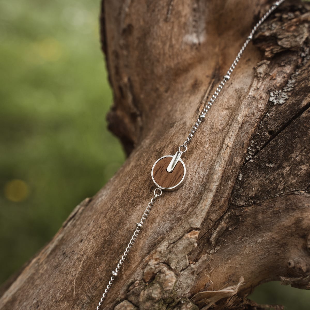 Bracciale "Opacity" con un design in noce e argento su uno sfondo rustico.