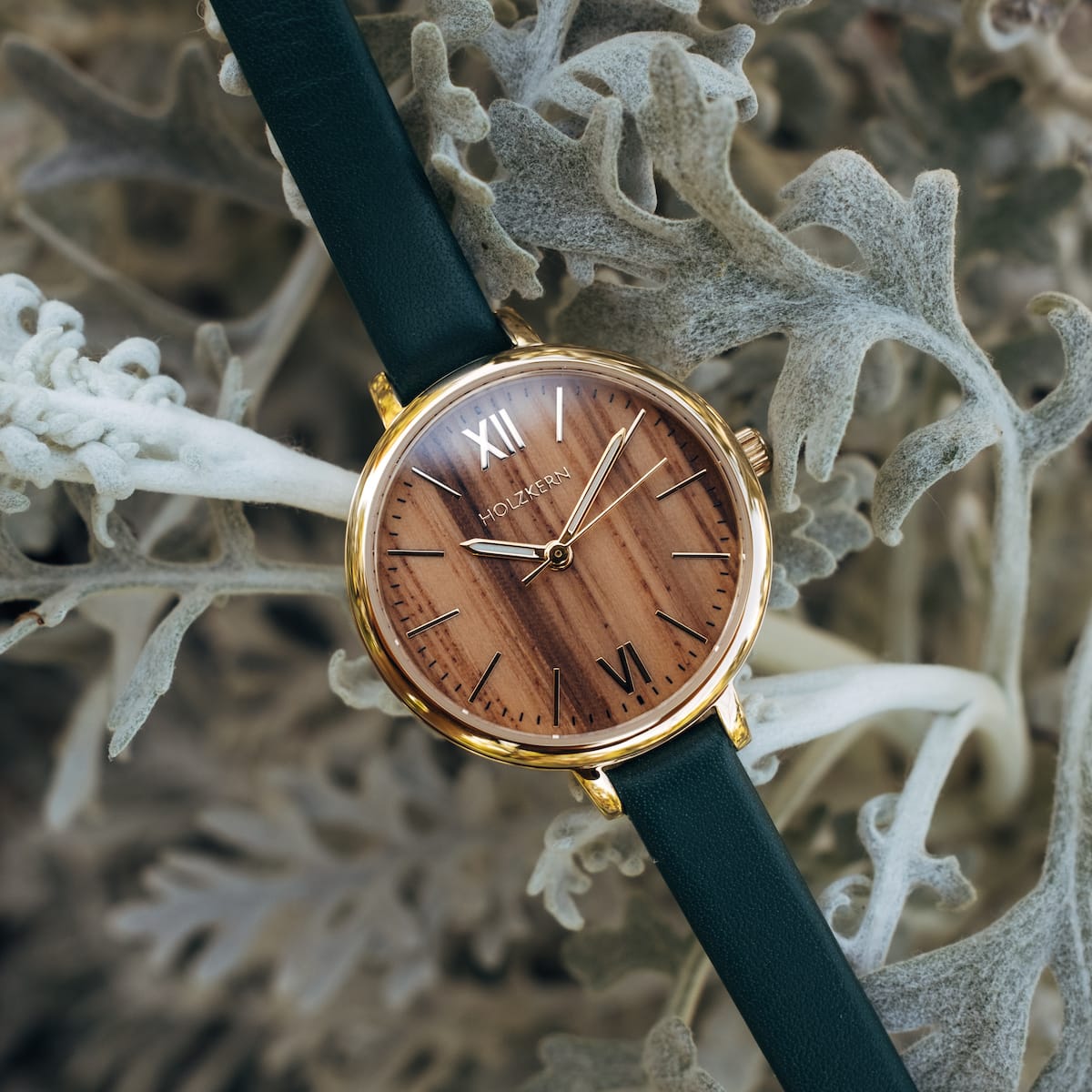 "Wangari" watch featuring zebrawood face and gold accents against a nature-inspired background.