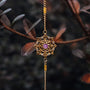 Bracciale "Aphonia" con intricato design oro con centrotavola ametista, impostato su uno sfondo ispirato alla natura.