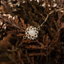 "Composition Gem Bracelet", an elegant bracelet with moonstone and gold accents, nestled in rustic foliage.
