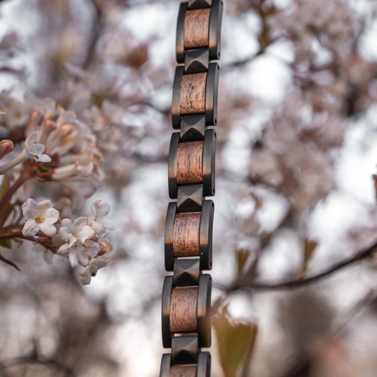 Bracciale "Rhapsody" con accenti in noce e nero in un ambiente naturale.