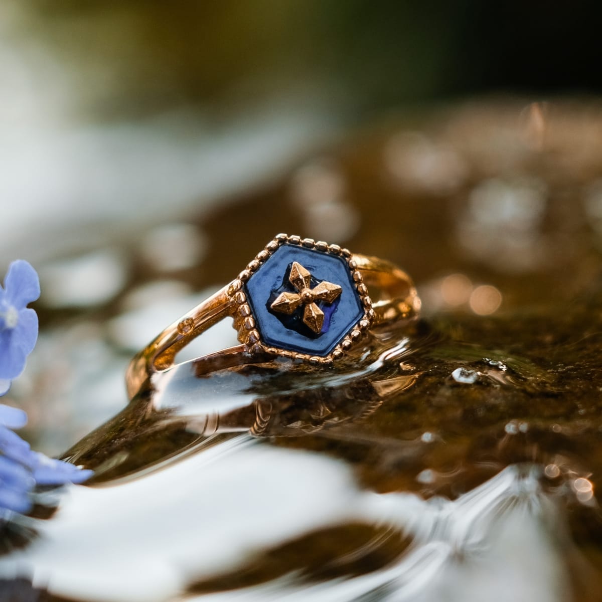 "Spectral Ring", un anello in oro con intarsio blu nacre, caratterizzato da un design geometrico intricato.