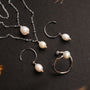 Elegant "Panoramic Necklace" necklace with white pearls and silver accents on a dark background.