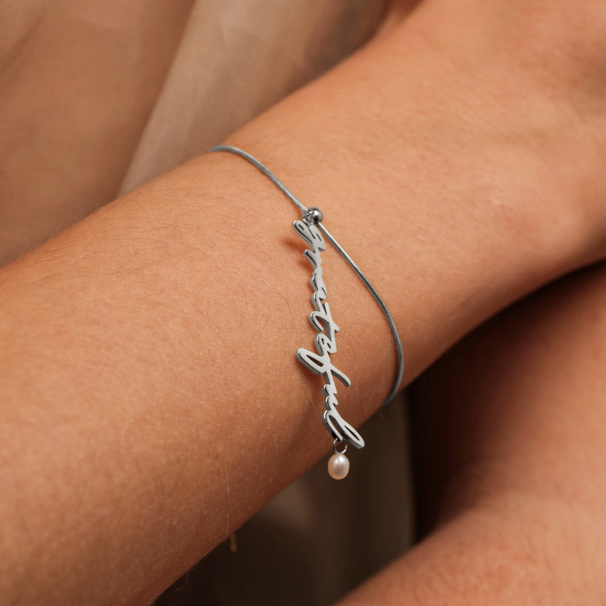 Bracciale "Grateful-Charm" con eleganti perle e un fascino argento con un design minimalista sul polso.