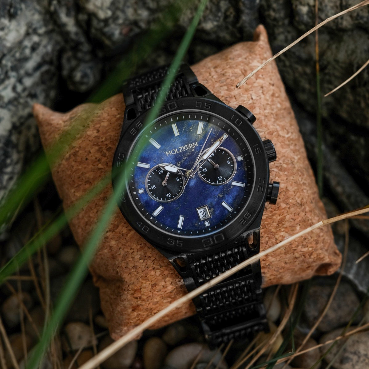 L'orologio "Aoraki" presenta un sorprendente Lapis Lazuli faccia e design nero elegante, impostato su uno sfondo naturale.