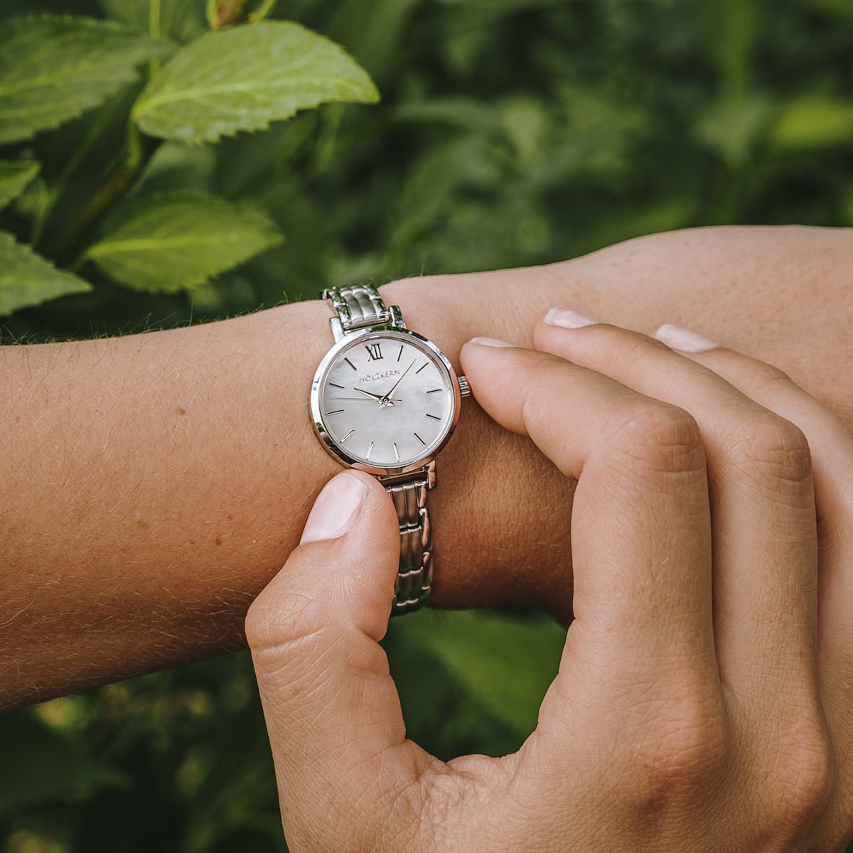 "Skadi" watch in nacre and silver, showcasing elegant design against a natural background.