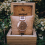 Orologio "Belvue" con cassa e cinturino in noce, presentato in uno stile naturale ed elegante su uno sfondo floreale.