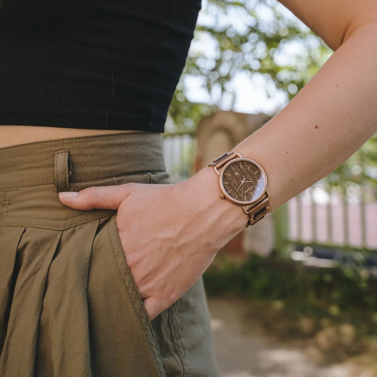 Orologio "Belvue" in legno di noce, caratterizzato da un design elegante e minimalista indossato da una persona all'aperto.