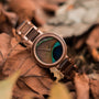 "The Optimist" - Elegante orologio con finitura noce e design in piuma pavone sul quadrante.